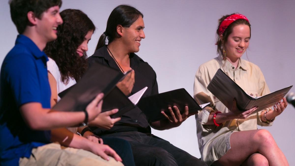 Students sitting in a circle reading scripts.